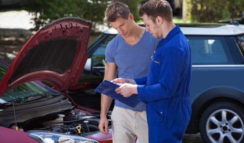 Mechanic Showing Clipboard To Customer By Breakdown Car