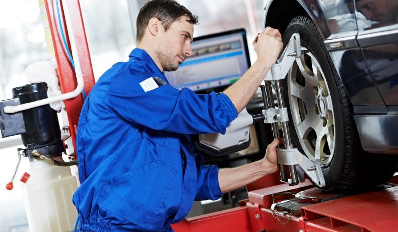 auto mechanic at wheel alignment work with spanner